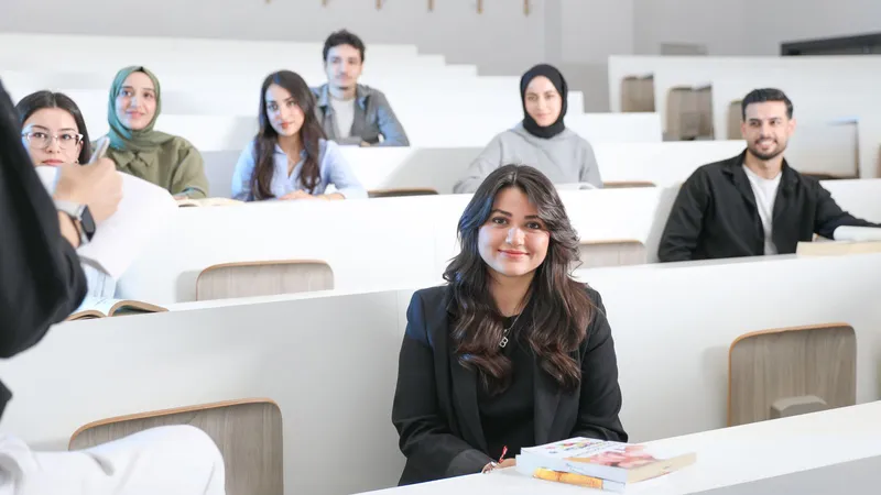 Étudiants assis dans un amphithéâtre universitaire aux bancs blancs, pendant un cours