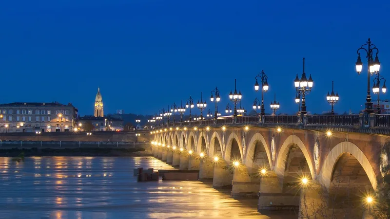Le pont de Pierre de Bordeaux illuminé à la tombée du jour, au-dessus de la Garonne