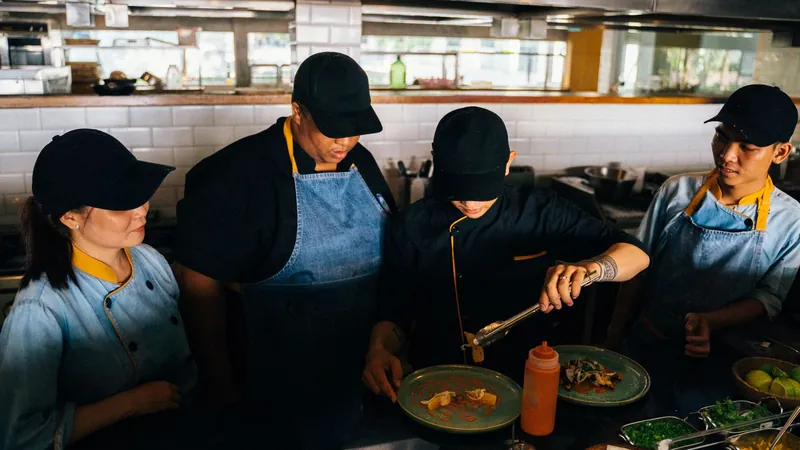 Une brigade de cuisiniers en tablier dresse des assiettes dans la cuisine d’un restaurant