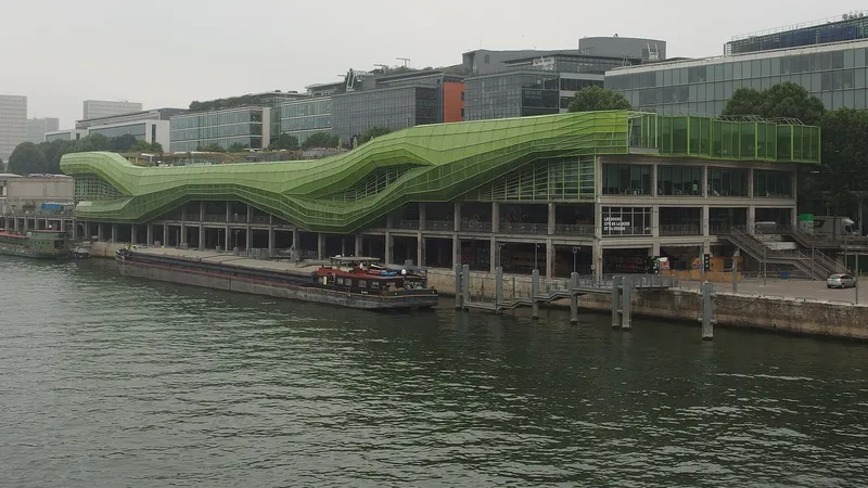 La Cité de la mode et du design à Paris, bâtiment de béton coiffé d’une structure vitrée verte ondulante, au bord de la Seine