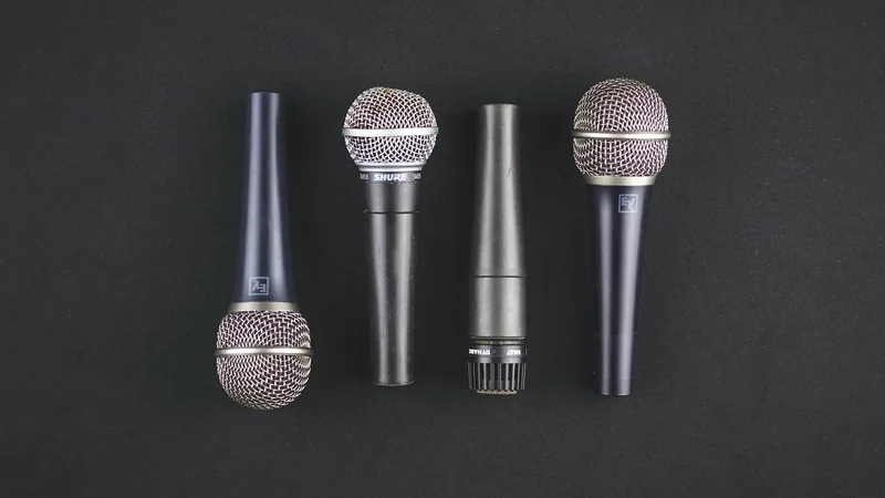 Quatre microphones alignés sur fond noir, univers des relations presse et de la communication